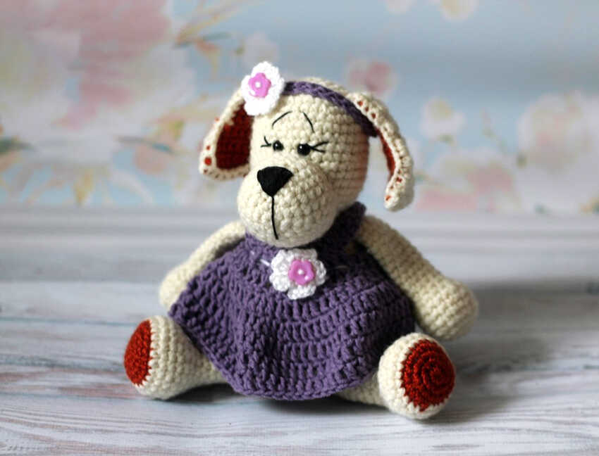 An inspirational visualization of the amigurumi puppy in a purple dress, providing a stylistic preview of our free crochet pattern. It serves as a professional reference for customizing your handmade project. We provide this creative concept to help you visualize the final outfit details.