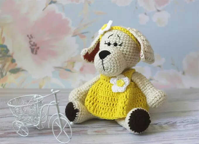 A high-quality visualization of the amigurumi puppy in a yellow dress, serving as a stylistic preview for our free pattern guide. This image highlights the texture and design as a professional reference for your crochet work. We share this artistic concept to inspire your handmade gift ideas.