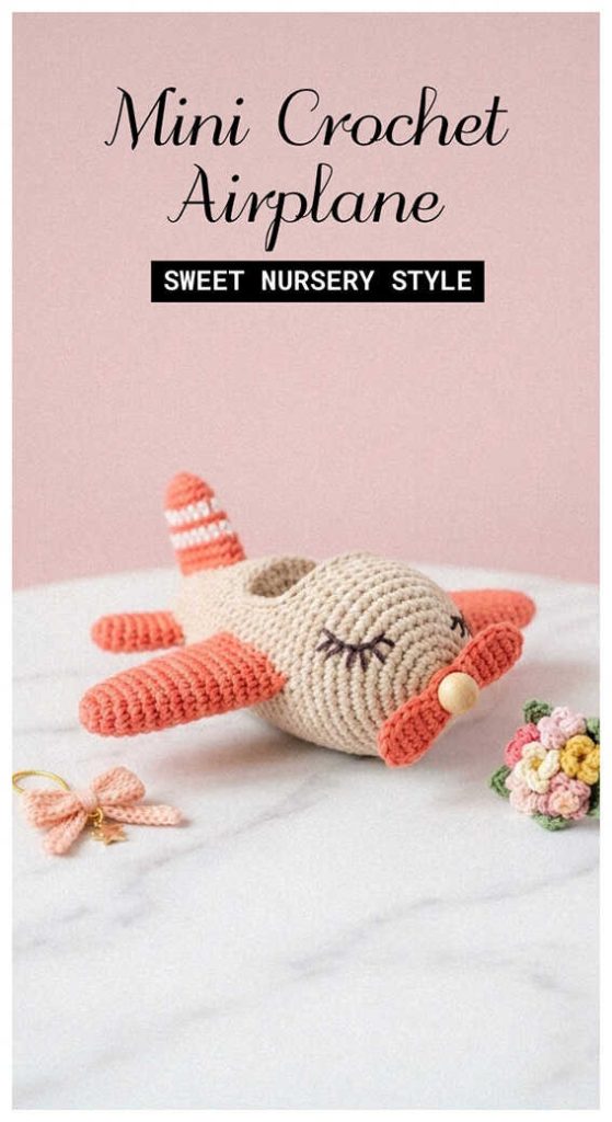 Mini crochet airplane in soft coral tones displayed on marble table, styled as a handmade baby gift for sweet nursery style decor.