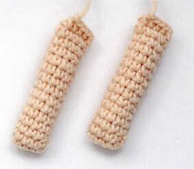 Amigurumi doll arms crochet pieces shown before assembly, small tubular arm parts crocheted in skin tone yarn for the Bjashik amigurumi character.