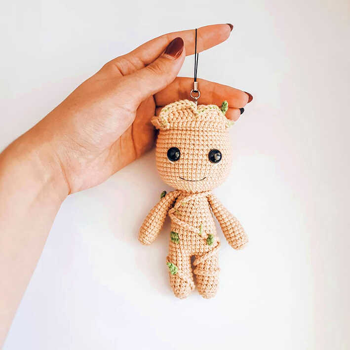 Baby Groot amigurumi crochet keychain held in hand with cute tree details, small handmade character toy, free crochet pattern for gift or bag charm.