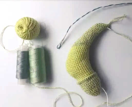 Chameleon amigurumi crochet body with yarn and tools shown during process, handmade lizard toy base prepared before assembly for crochet pattern.