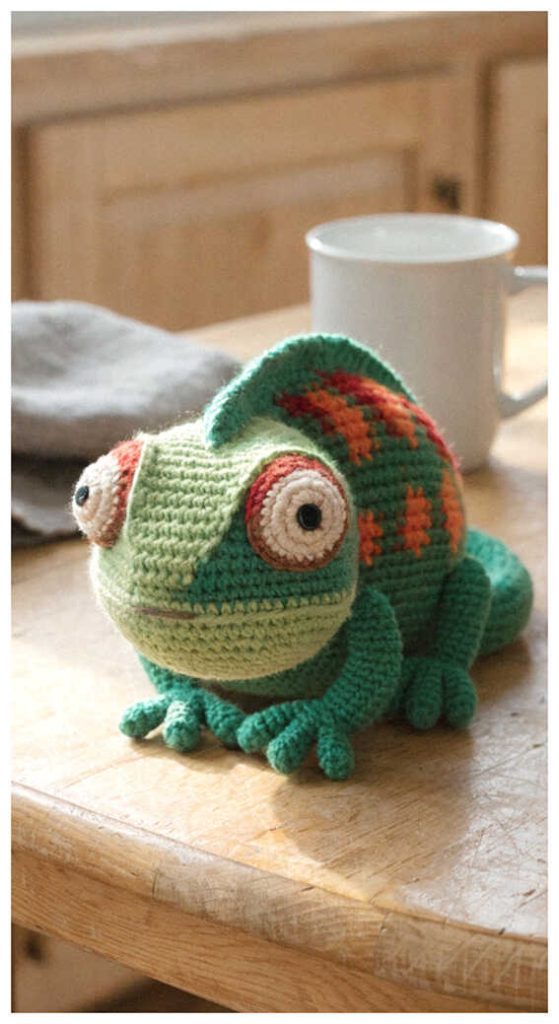 Chameleon amigurumi crochet toy with colorful details on table, you’ll want to make this unique design, free pattern available in the link for cute gifts.