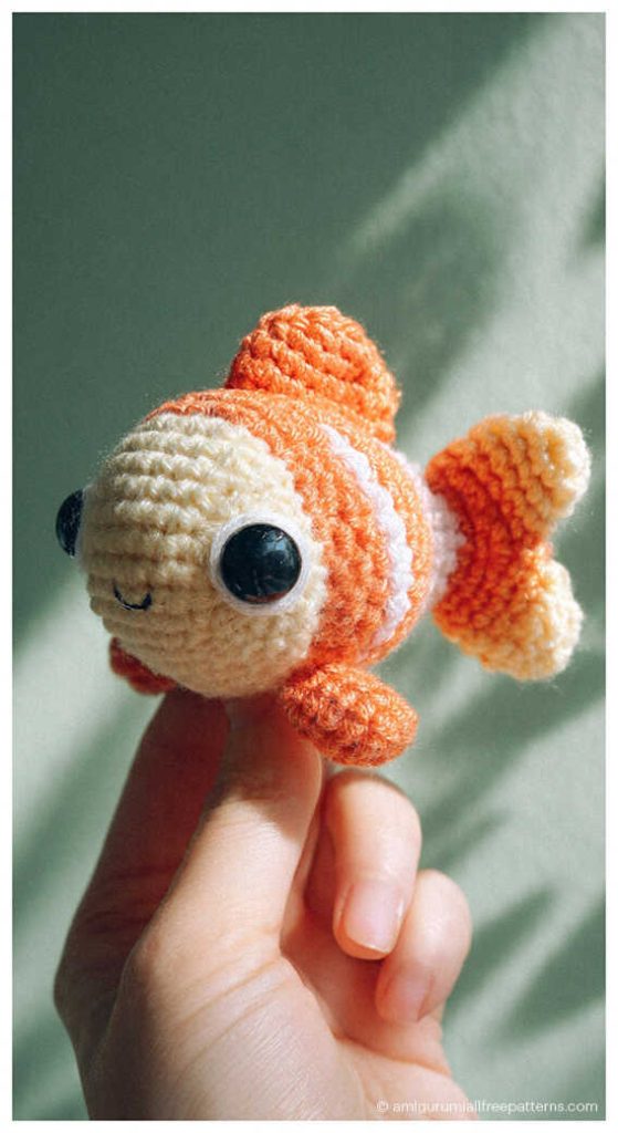 Fish amigurumi crochet doll with bright orange details held in hand, cute handmade plush you’ll love for nursery decor or gift idea.