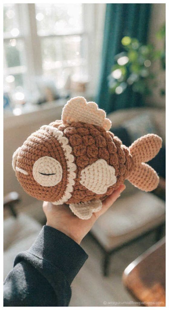 Fish amigurumi crochet plush in neutral tones held in hand, cozy handmade toy you’ll love for nursery decor or a thoughtful crochet gift.
