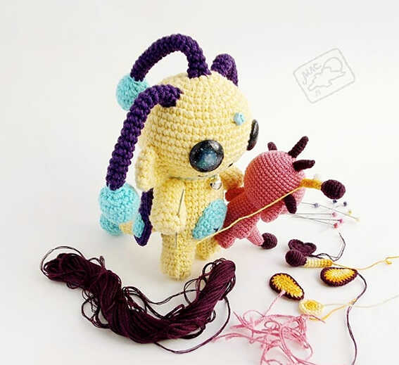Kawaii alien amigurumi crochet toy with shiny galaxy eyes and playful colors, handmade sci-fi plush character, free crochet pattern for a fun handmade gift.