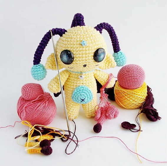 Small alien amigurumi crochet plush with cosmic eyes and cute space design, handmade toy character, free crochet pattern for nursery decor or gift idea.
