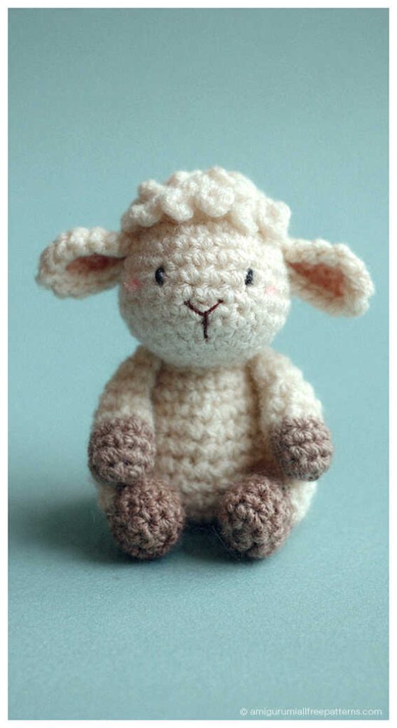 Little lamb amigurumi crochet plush with fluffy texture sitting on blue background, cozy handmade toy perfect for nursery decor or sweet handmade gift.