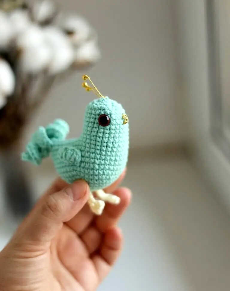 Cute spring bird amigurumi crochet toy held in hand, free crochet pattern available, perfect for small handmade gifts and spring themed decor.