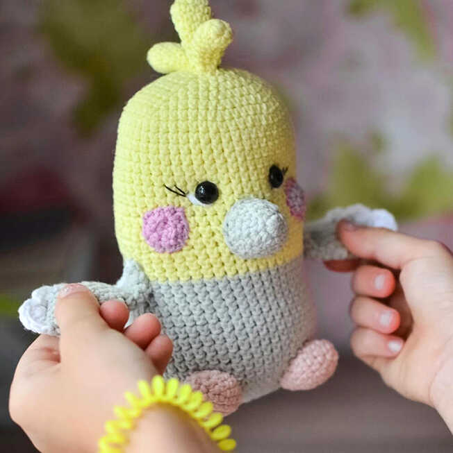 Close up of parrot amigurumi free crochet pattern with yellow and grey yarn, cute handmade bird toy with soft texture