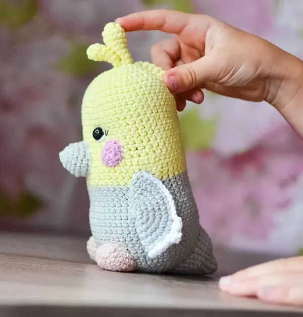 Side view of parrot amigurumi free crochet pattern with soft yarn, cute handmade bird toy with wings and beak details