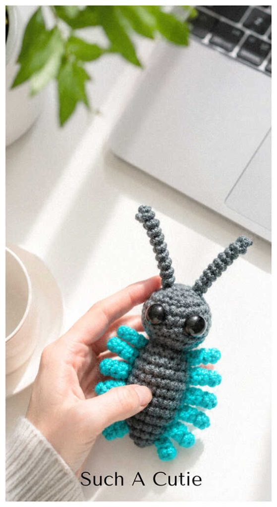 Blue crochet bug amigurumi held in hand in a bright room