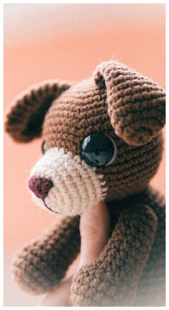 Brown puppy crochet plush displayed on a warm pastel background
