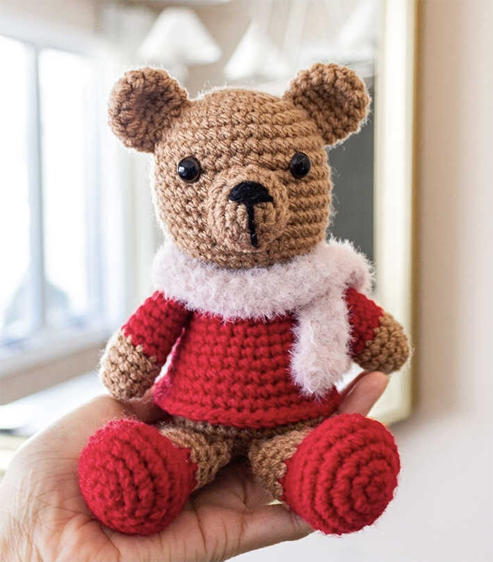 Christmas crochet bear amigurumi plush held in hand with red sweater and scarf