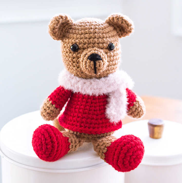 Cute Christmas crochet bear amigurumi plush in red sweater displayed indoors