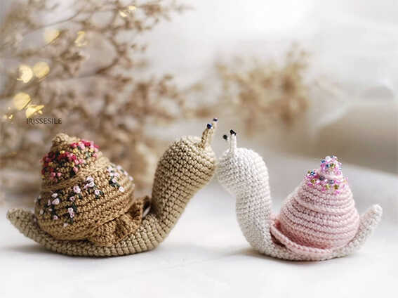 Cute crochet snail amigurumi pair displayed in a soft cozy setting