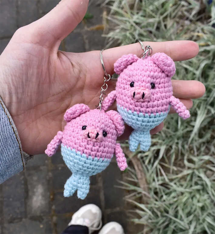 Cute pig mermaid crochet keychains held in hand outdoors