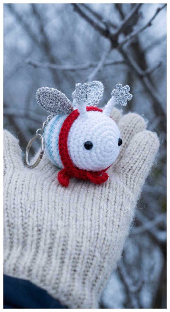 Mini bee amigurumi plush displayed on a knitted glove outdoors