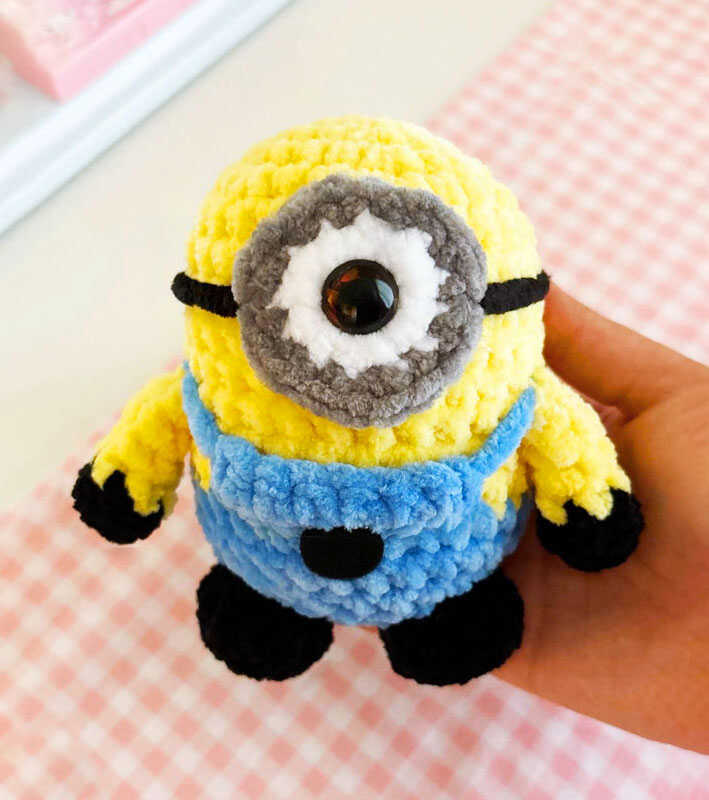 Minion amigurumi crochet plush held in hand in a bright indoor setting