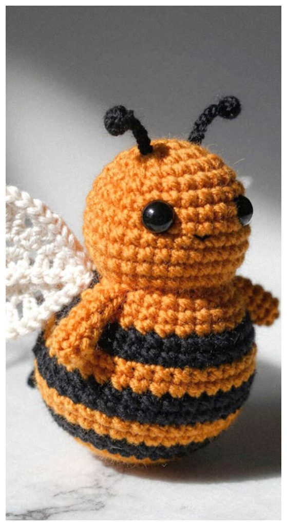 Orange bee amigurumi plush displayed on a soft neutral background
