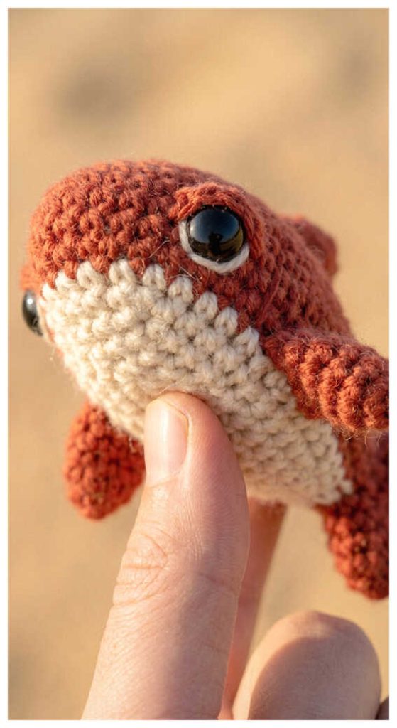Orange shark crochet plush toy held in hand