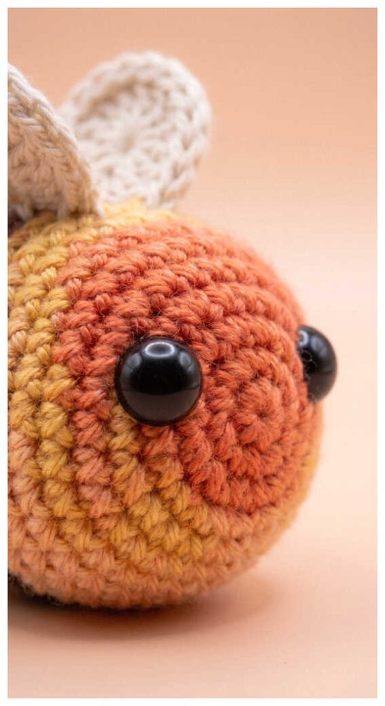 Round bee crochet plush close up on a soft pastel background