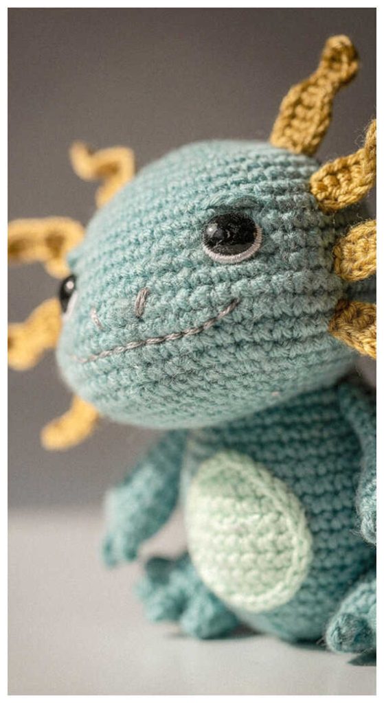 Teal axolotl crochet plush displayed in a cozy indoor setting