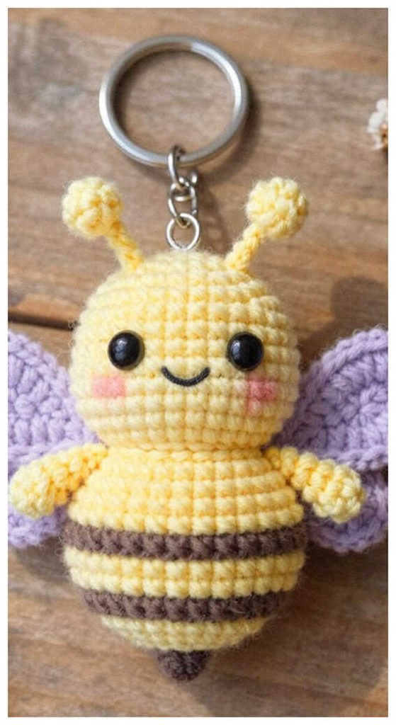 Tiny bee keychain amigurumi plush displayed on a wooden surface