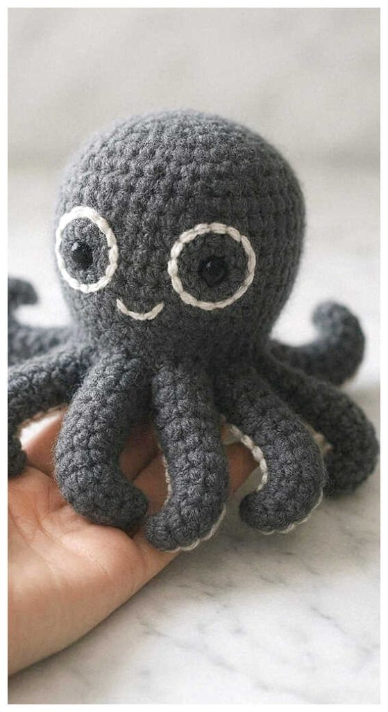 Tiny black octopus amigurumi plush held in hand indoors
