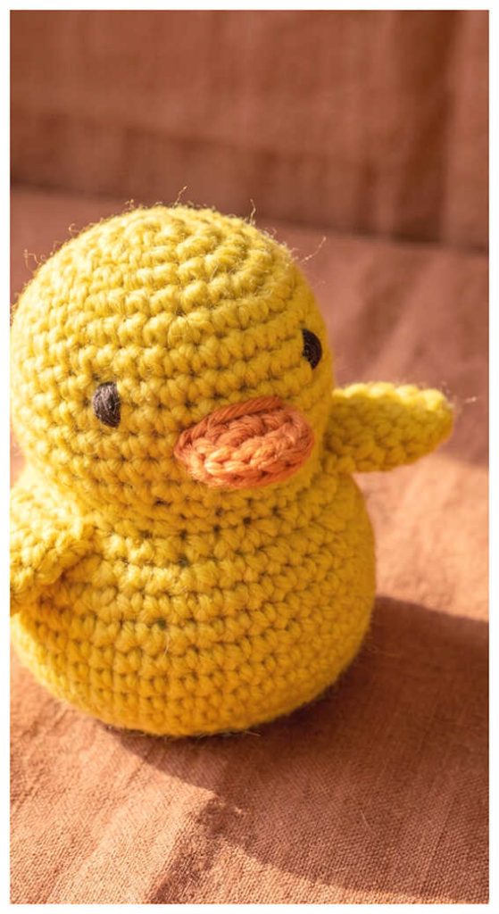 Yellow duck amigurumi plush displayed on a wooden surface